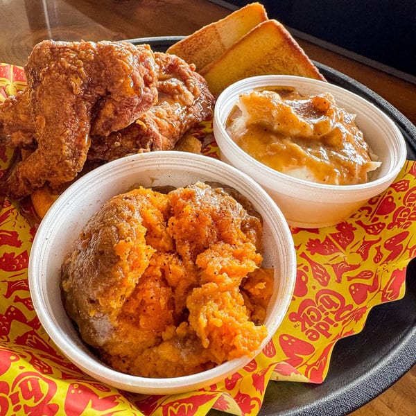 Fried chicken, mashed potatoes with gravy, sweet potato casserole, and toast on a tray.