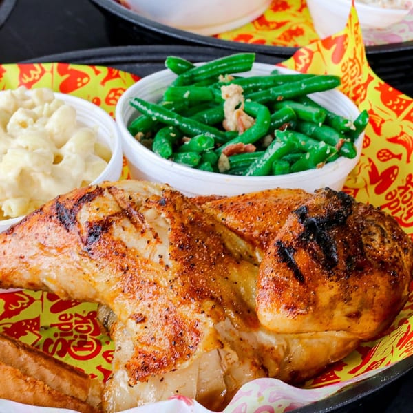 Grilled chicken with sides of macaroni and cheese and green beans with bacon bits.